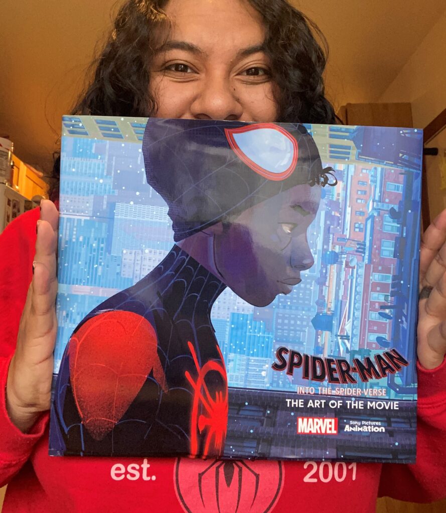 Office Assistant Carmen Rodriguez holds book about the art of the movie "Into the Spider-Verse"